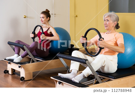 Two women perform exercises using special fitness rings and a fitball Two women perform exercises using special fitness rings and a fitball 112788948