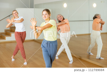 Teen girl with family doing aerobics exercises with group of people in dance center Teen girl with family doing aerobics exercises with group of people in dance center 112789084