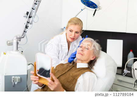 Female cosmetologist consulting aged woman before facial treatments 112789184
