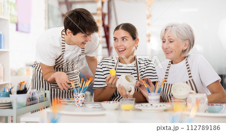 Group of cheerful people painting ceramic dishware in pottery class 112789186