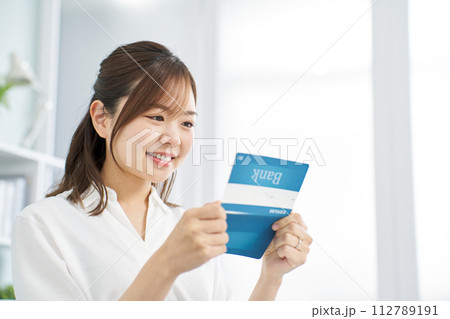 笑顔で銀行の通帳を見る女性 笑顔で銀行の通帳を見る女性 112789191