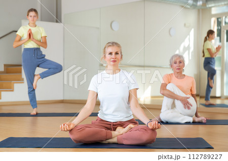 Group of women and teen girl doing yoga Padmasana exercise, Lotus pose 112789227