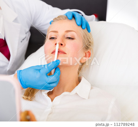 Cosmetologist hands making marks on face of female patient prior to surgery Cosmetologist hands making marks on face of female patient prior to surgery 112789248