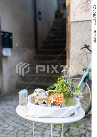 Bicycle parked by table with vase of flowers and homemade jams on it Bicycle parked by table with vase of flowers and homemade jams on it 112790425
