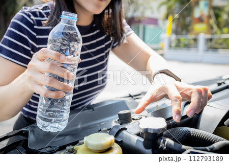 Woman check the radiator system and fluid level in the car radiator is too low after engine overheated,she uses water instead of coolant during traveling,emergency,repair,service,maintenance concept Woman check the radiator system and fluid level in the car radiator is too low after engine overheated,she uses water instead of coolant during traveling,emergency,repair,service,maintenance concept 112793189