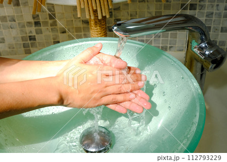 Hands of woman wash their hands in a sink with foam to wash the skin and water flows through the hands. Concept of health, cleaning and preventing germs and coronavirus from contacting hands 112793229