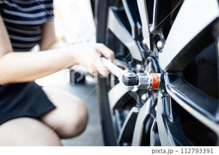 Socket wrench tool in hands of woman,closing screws the bolts,tighten the nuts or unscrews the wheel nuts,change wheel,checking the car tires before traveling,maintenance,service and repair concept 112793391