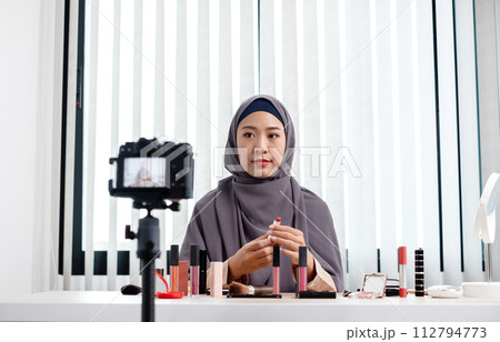 Muslim women making video beauty vlogger bloggers doing a cosmetic makeup tutorial vlog with brushes looking camera Save clips and share them on social media live via the internet Online 112794773