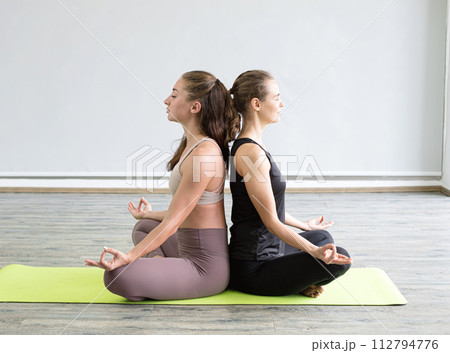 Two young women play yoga stretching, exercise for health in fitness, the concept of physical and mental health care 112794776