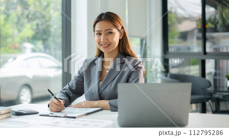 Asian businesswoman calculate financial graphs showing results about their investments, plan a successful business growth process Asian businesswoman calculate financial graphs showing results about their investments, plan a successful business growth process 112795286