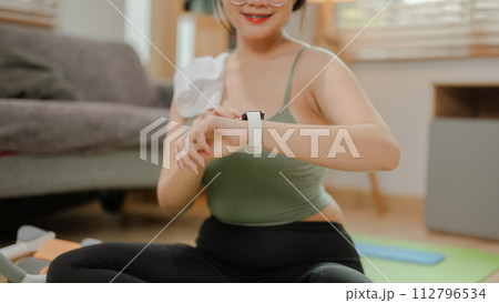 A fit Asian woman in sportswear is checking her heart rate and burnt calories on her smartwatch. 112796534