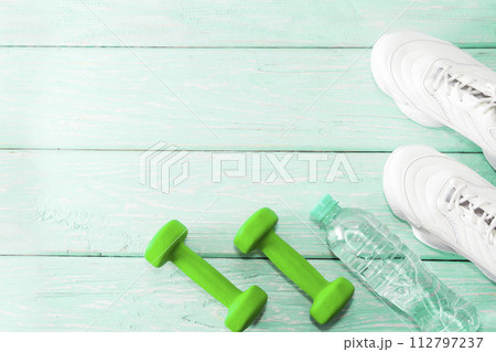 dumbbell sneakers on a bright background. Healthy lifestyle dumbbell sneakers on a bright background. Healthy lifestyle 112797237