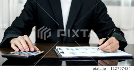 The businessman hand sits at their desks and calculates financial graphs showing the results of their investments planning the process of successful business growth 112797484