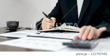 The businessman hand sits at their desks and calculates financial graphs showing the results of their investments planning the process of successful business growth The businessman hand sits at their desks and calculates financial graphs showing the results of their investments planning the process of successful business growth 112797485