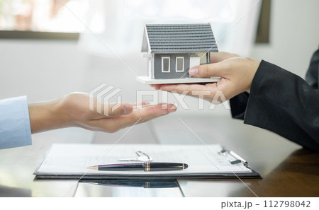 Real estate agent broker hand over the home to the new owner after completing the signing according to the agreement of renting a house and buying house insurance Home insurance concept 112798042