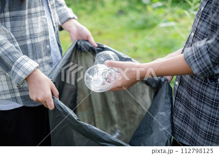garbage collection, volunteer team pick up plastic bottles, put garbage in black garbage bags to clean up at parks, avoid pollution, be friendly to the environment and ecosystem 112798125