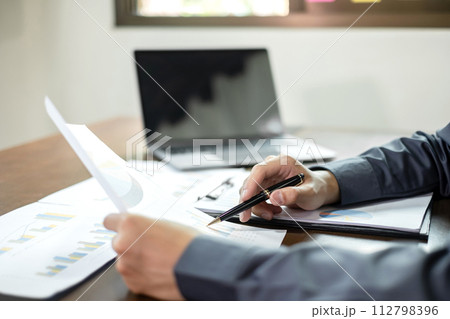 The businessman hand sits at their desks and calculate financial graphs showing results about their investments, planning a successful business growth process The businessman hand sits at their desks and calculate financial graphs showing results about their investments, planning a successful business growth process 112798396