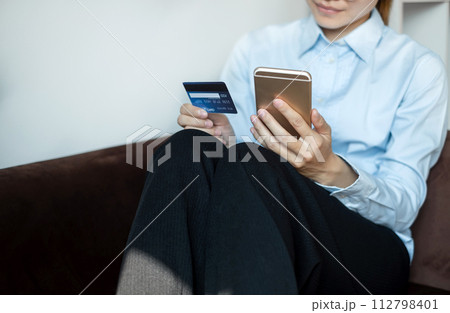 Asian girl shopping online holding credit and using smartphone enter their card number in the mobile phone app to purchase and payment in internet store 112798401