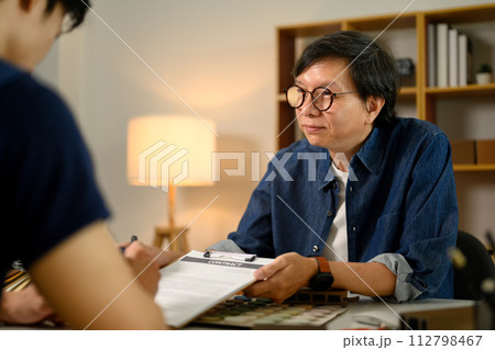 Male customer putting signature on agreement with contractor at office 112798467