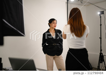 Elegant young female model posing for professional photographer in studio 112798484