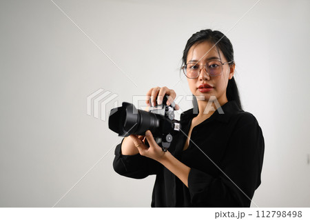 Beautiful female photographer with a dslr camera working at her studio 112798498