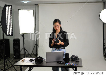 Young stylish woman with her DSLR camera working in professional photo studio 112798501
