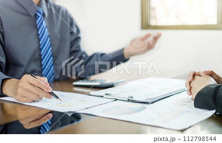 Two business leaders talk about charts, financial graphs showing results are analyzing and calculating planning strategies, business success building processes Two business leaders talk about charts, financial graphs showing results are analyzing and calculating planning strategies, business success building processes 112798544