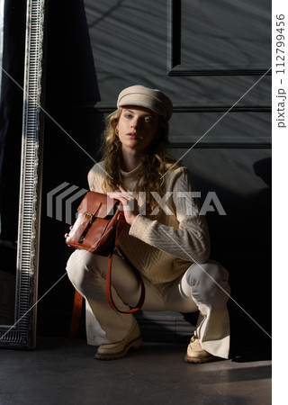 Studio portrait of beautiful woman with a curly blond hair holding brown bag, posing on gray background. Studio portrait of beautiful woman with a curly blond hair holding brown bag, posing on gray background. 112799456