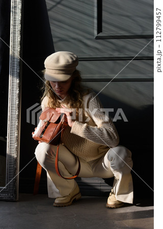 Studio portrait of beautiful woman with a curly blond hair holding brown bag, posing on gray background. 112799457