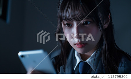 暗い部屋でスマホを見る女子学生 暗い部屋でスマホを見る女子学生 112799802