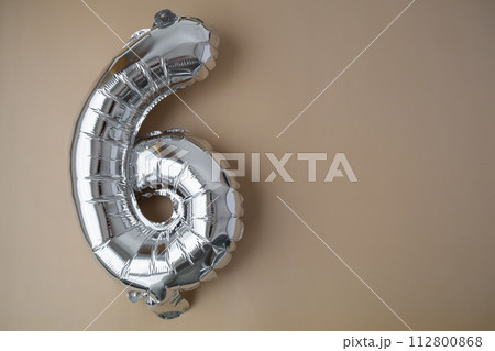 6 six metallic balloon on beige neutral background. Greeting card silver foil balloon number Happy birthday holiday concept. Copy space for text. Celebration party congratulation 112800868