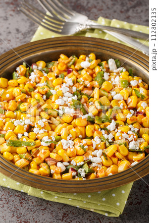 Esquites Mexican Street Corn Salad with jalapeno, cilantro, Cotija cheese, onion and spices close-up on the plate. Vertical Esquites Mexican Street Corn Salad with jalapeno, cilantro, Cotija cheese, onion and spices close-up on the plate. Vertical 112802135