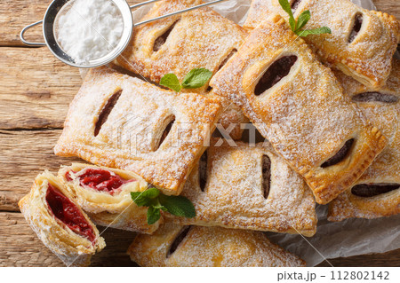 Sweet berry puff pastry with powdered sugar and mint close-up. Horizontal top view 112802142