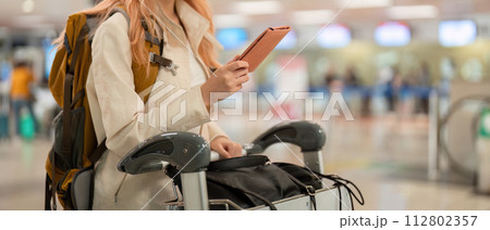 Hand of woman passenger holding passport with the flight in airport terminal 112802357