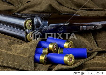 Vintage Shotgun with Shotgun Cartridges on an Outdoor Field Coat Vintage Shotgun with Shotgun Cartridges on an Outdoor Field Coat 112802591