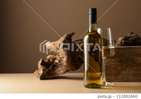 White wine and old snag on a beige background. 112802660