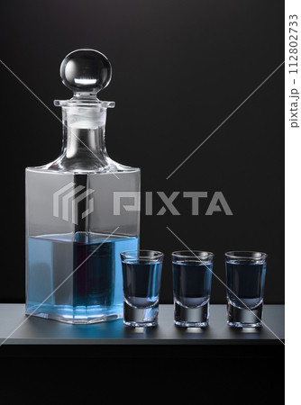 Old decanter and glasses with blue gin. Old decanter and glasses with blue gin. 112802733