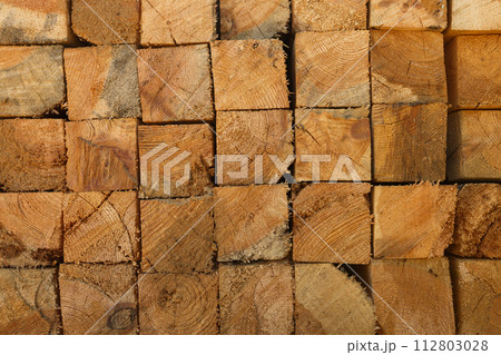 Stacked lumber texture showcasing natural wood grain. Perfect for background in architecture, construction, carpentry, or eco-friendly material themes. 112803028