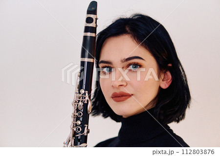 Graceful Brunette Musician Posing with Clarinet on White Background 112803876