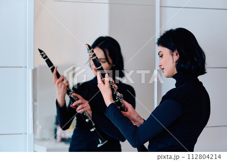 Graceful Brunette Musician Posing with Clarinet on White Background Graceful Brunette Musician Posing with Clarinet on White Background 112804214