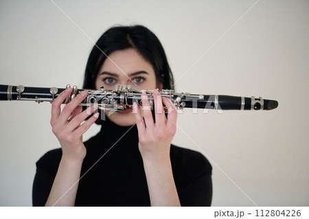 Graceful Brunette Musician Posing with Clarinet on White Background 112804226