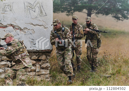 In a high stakes mission, a specialized military unit executes a tactical operation to secure a dangerous house where terrorists are believed to be hiding, showcasing precision and coordinated In a high stakes mission, a specialized military unit executes a tactical operation to secure a dangerous house where terrorists are believed to be hiding, showcasing precision and coordinated 112804502