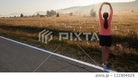 Determined Stretch: Athletic Woman Embraces Post-Run Flexibility in Nature. Determined Stretch: Athletic Woman Embraces Post-Run Flexibility in Nature. 112804828