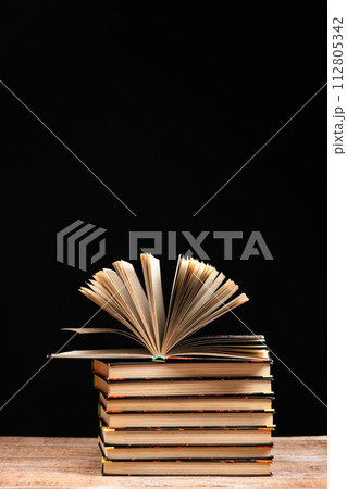 Stack of books on black background, open book, space for text. 112805342