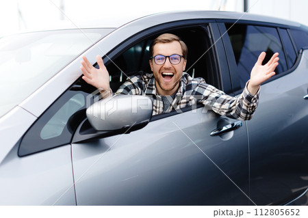 Man customer sitting in car salon and smiling, choosing auto and wanting to buy new automobile in showroom dealership store. Car sales concept. 112805652