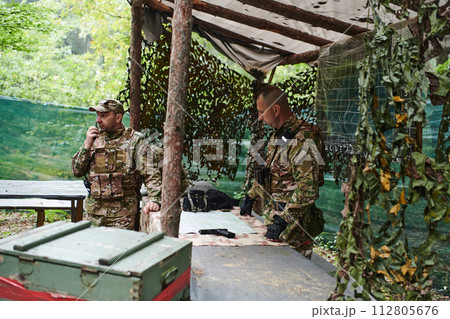 A highly trained military unit strategizes and organizes a tactical mission while studying a military map during a briefing session A highly trained military unit strategizes and organizes a tactical mission while studying a military map during a briefing session 112805676