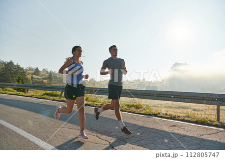 Energized by the beauty of nature, a couple powers through their morning run, their bodies and spirits invigorated. Energized by the beauty of nature, a couple powers through their morning run, their bodies and spirits invigorated. 112805747