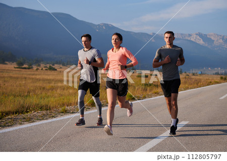 A group of friends maintains a healthy lifestyle by running outdoors on a sunny day, bonding over fitness and enjoying the energizing effects of exercise and nature A group of friends maintains a healthy lifestyle by running outdoors on a sunny day, bonding over fitness and enjoying the energizing effects of exercise and nature 112805797