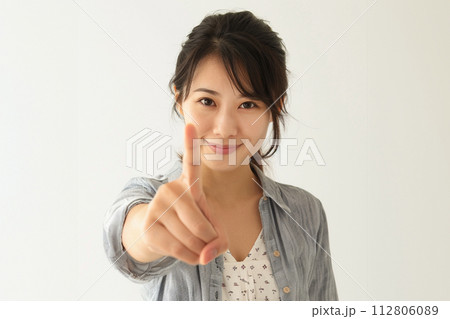 人差し指を前に出してポーズをとる若い女性 112806089