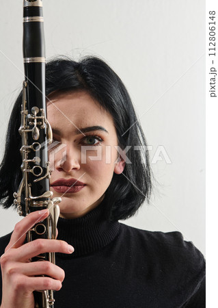 Graceful Brunette Musician Posing with Clarinet on White Background 112806148